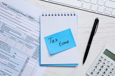 Photo of Reminder note with words Tax Time, documents and calculator on white wooden table, flat lay