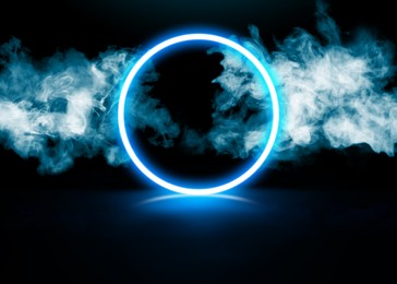 Image of Glowing round blue neon frame in smoke on black background