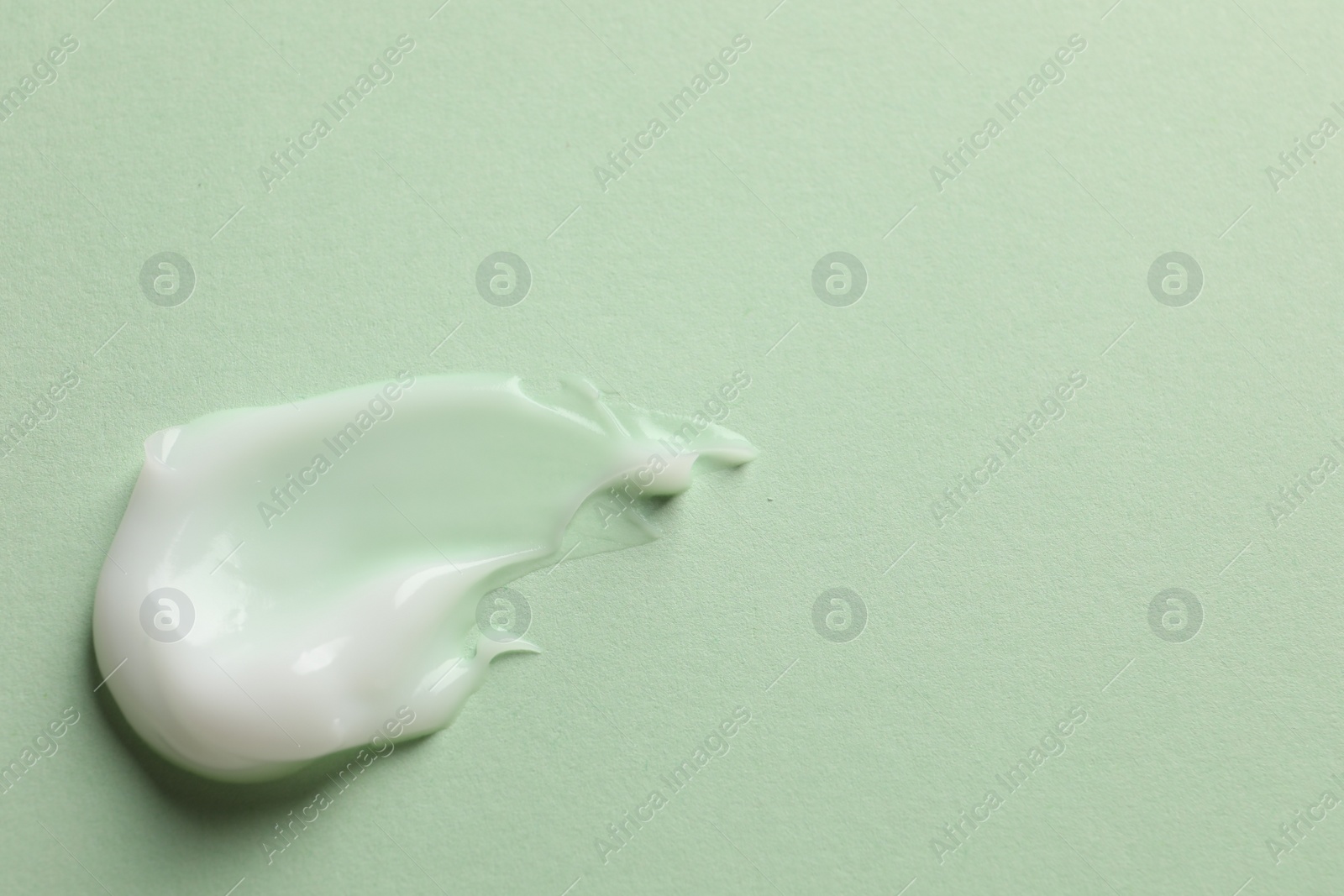 Photo of Sample of face cream on light green background, top view. Space for text