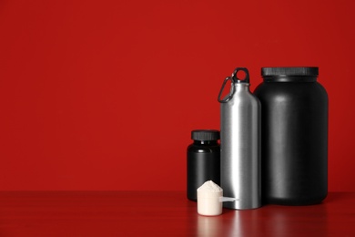 Photo of Composition with protein powder and black jars on table against red background