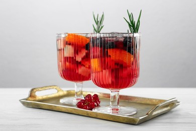 Photo of Glasses of Red Sangria on white wooden table against light grey background