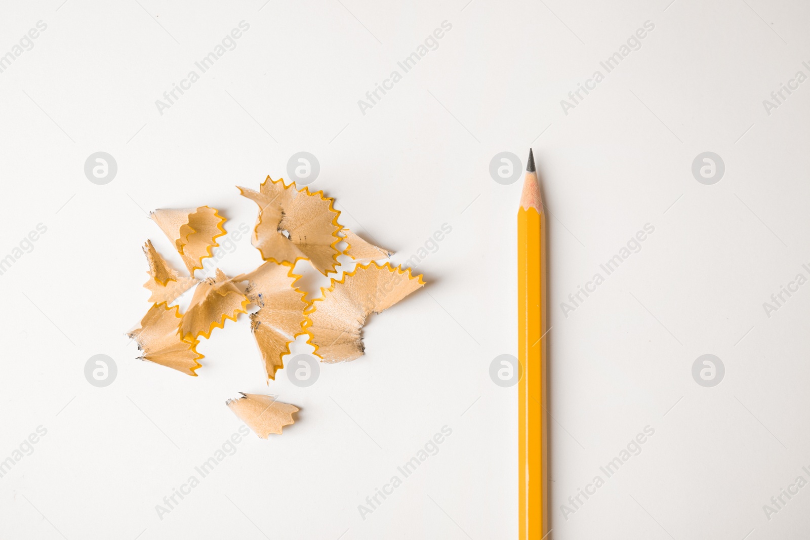 Photo of Pencil and shavings on white background, top view