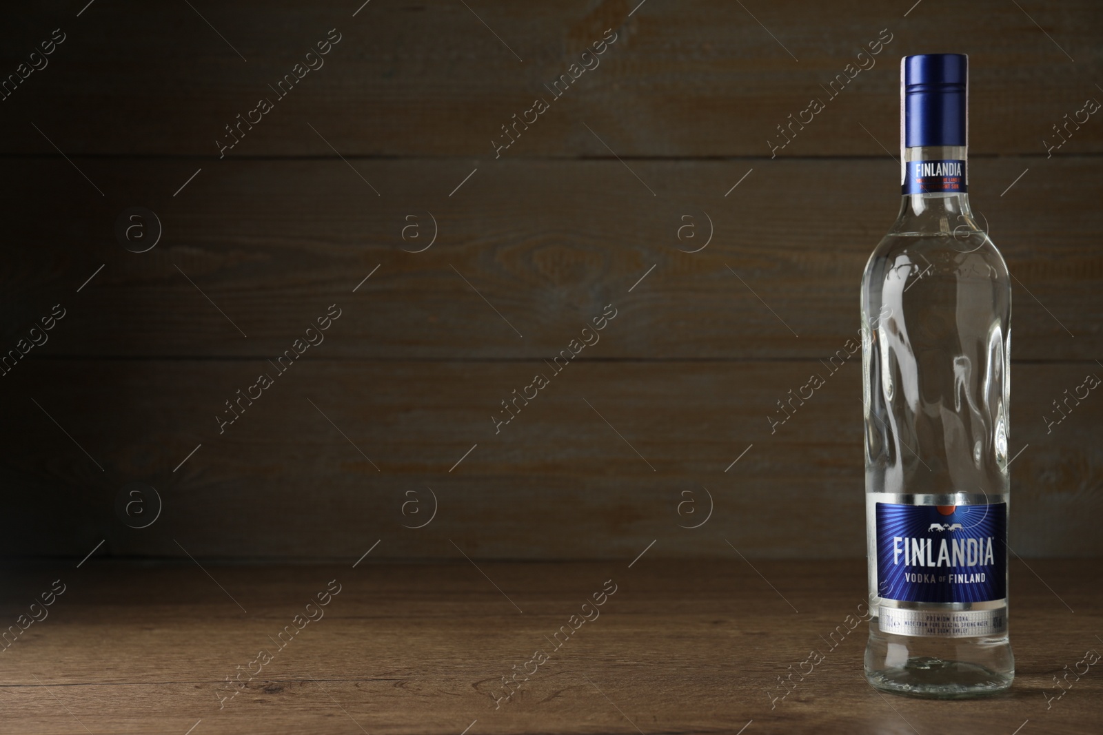 Photo of MYKOLAIV, UKRAINE - OCTOBER 03, 2019: Bottle of Finlandia vodka on table against wooden background. Space for text