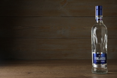 Photo of MYKOLAIV, UKRAINE - OCTOBER 03, 2019: Bottle of Finlandia vodka on table against wooden background. Space for text