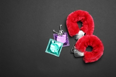 Photo of Furry handcuffs and condoms on black background, top view with space for text. Sex game