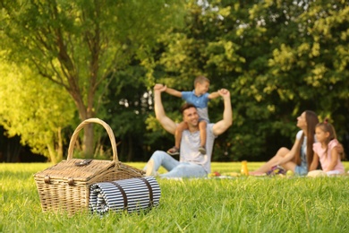 Photo of Picnic basket and happy family on background in park