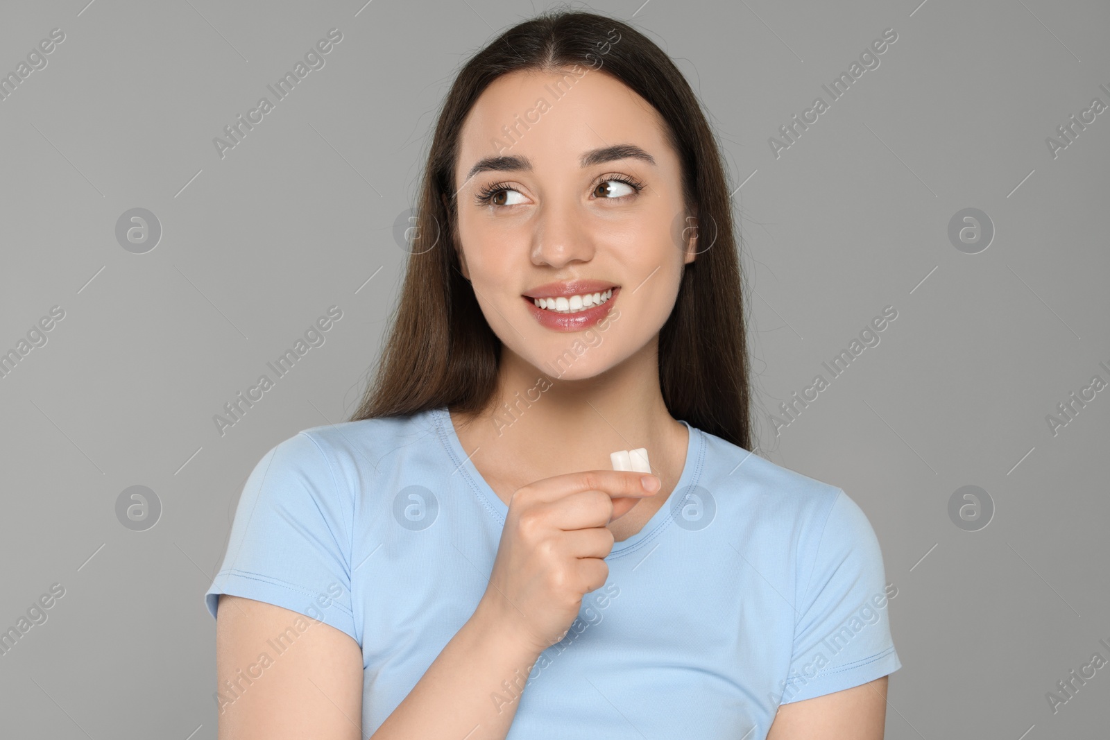 Photo of Happy young woman with bubble gums on grey background