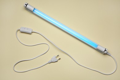 Ultraviolet lamp on beige background, top view