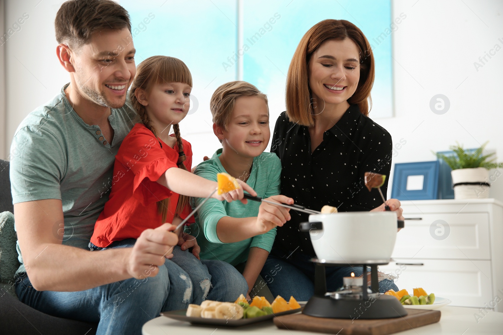 Photo of Happy family enjoying fondue dinner at home