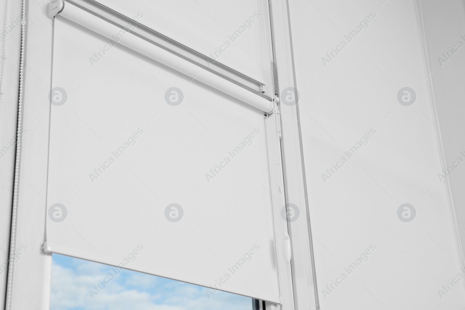 Photo of Window covered with white roller blinds indoors