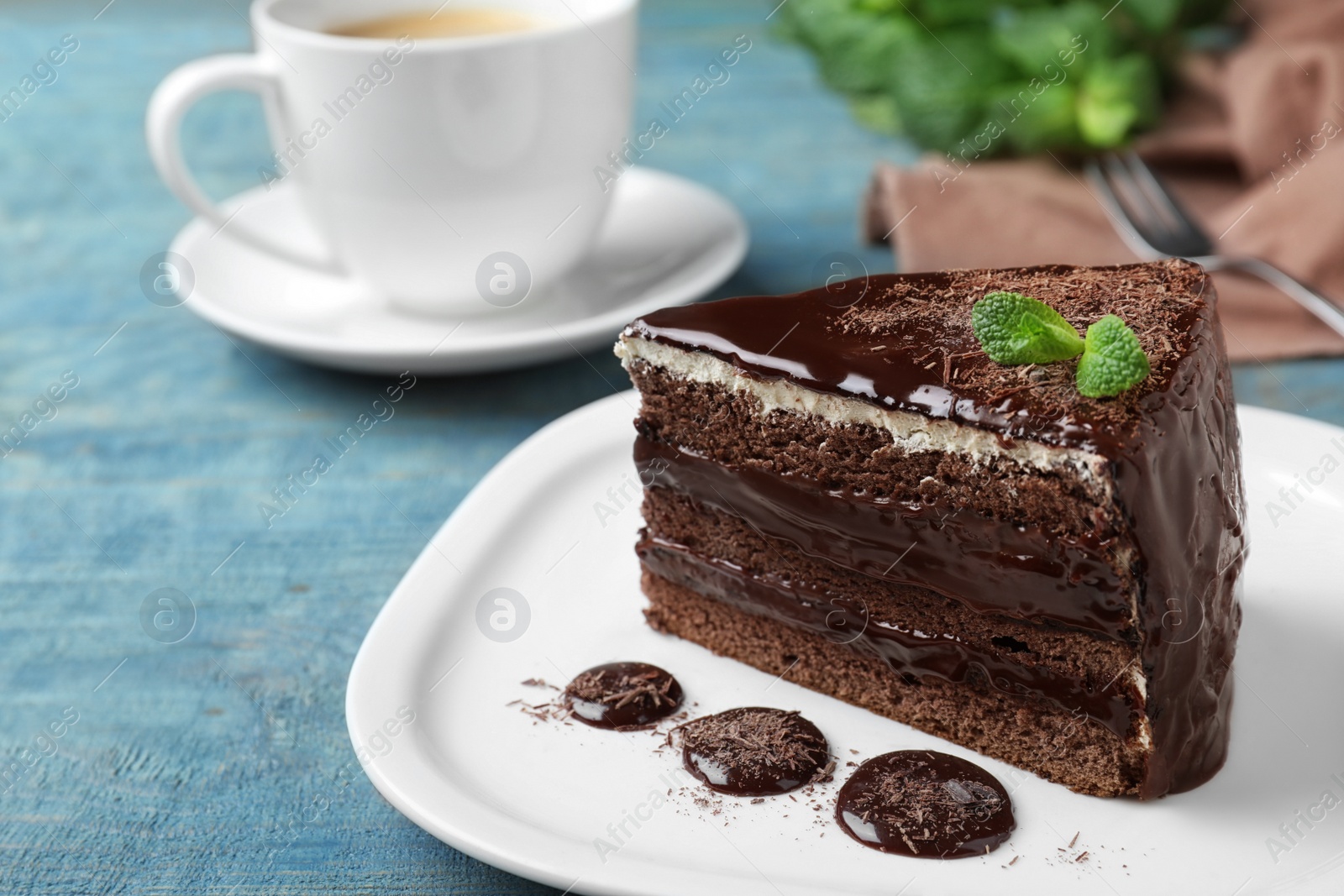 Photo of Delicious chocolate cake with mint on light blue wooden table, closeup