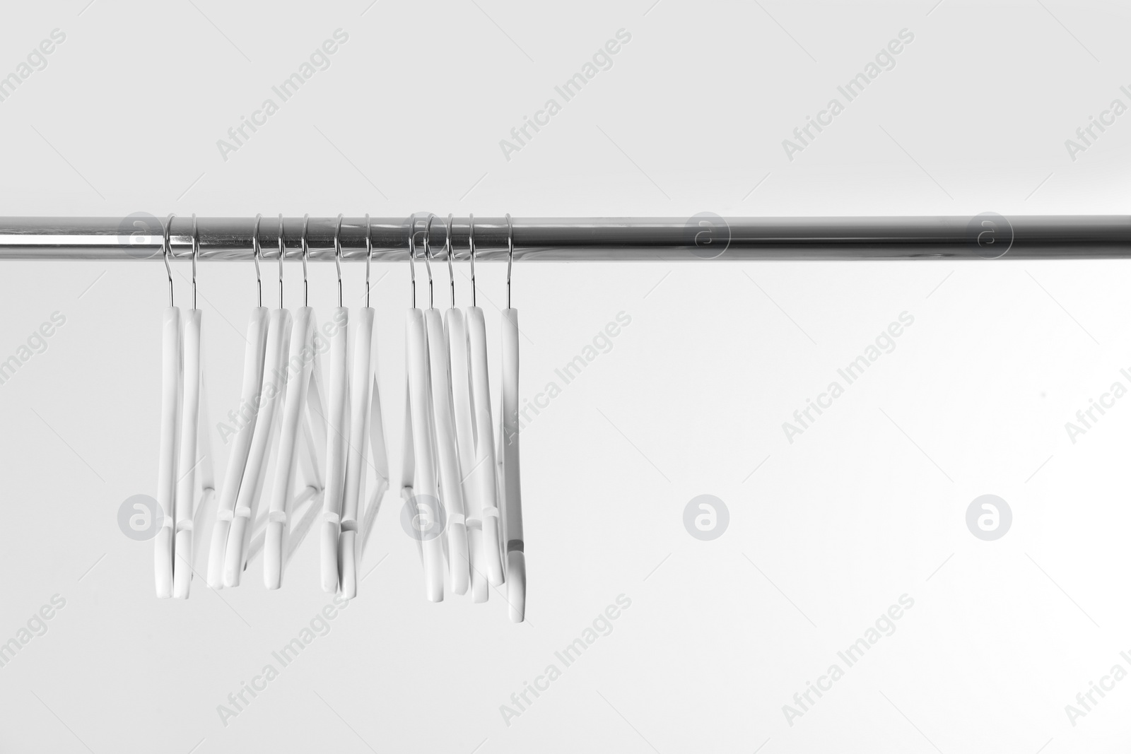 Photo of Metal rack with clothes hangers on white background, space for text