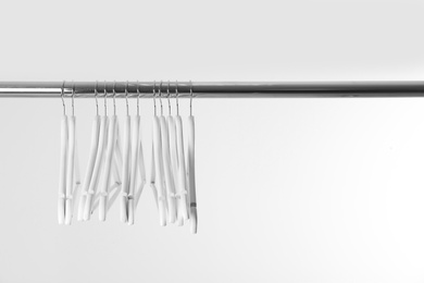 Metal rack with clothes hangers on white background, space for text