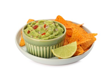 Photo of Bowl of delicious guacamole, lime and nachos chips isolated on white