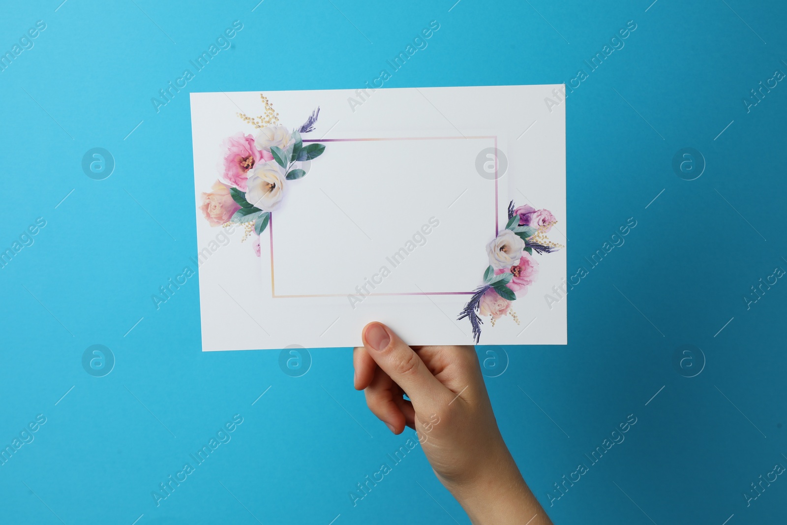 Photo of Woman holding blank invitation card on light blue background, closeup. Space for text