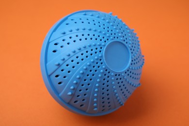 Photo of Dryer ball for washing machine on orange background. Laundry detergent substitute