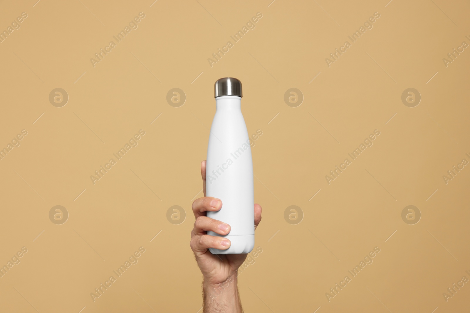 Photo of Man holding thermo bottle on beige background, closeup