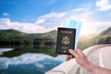 Image of Man holding passport and protective mask outdoors, closeup. Travel during quarantine