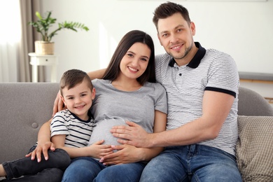 Father, son and pregnant mother spending time together on sofa at home. Family time