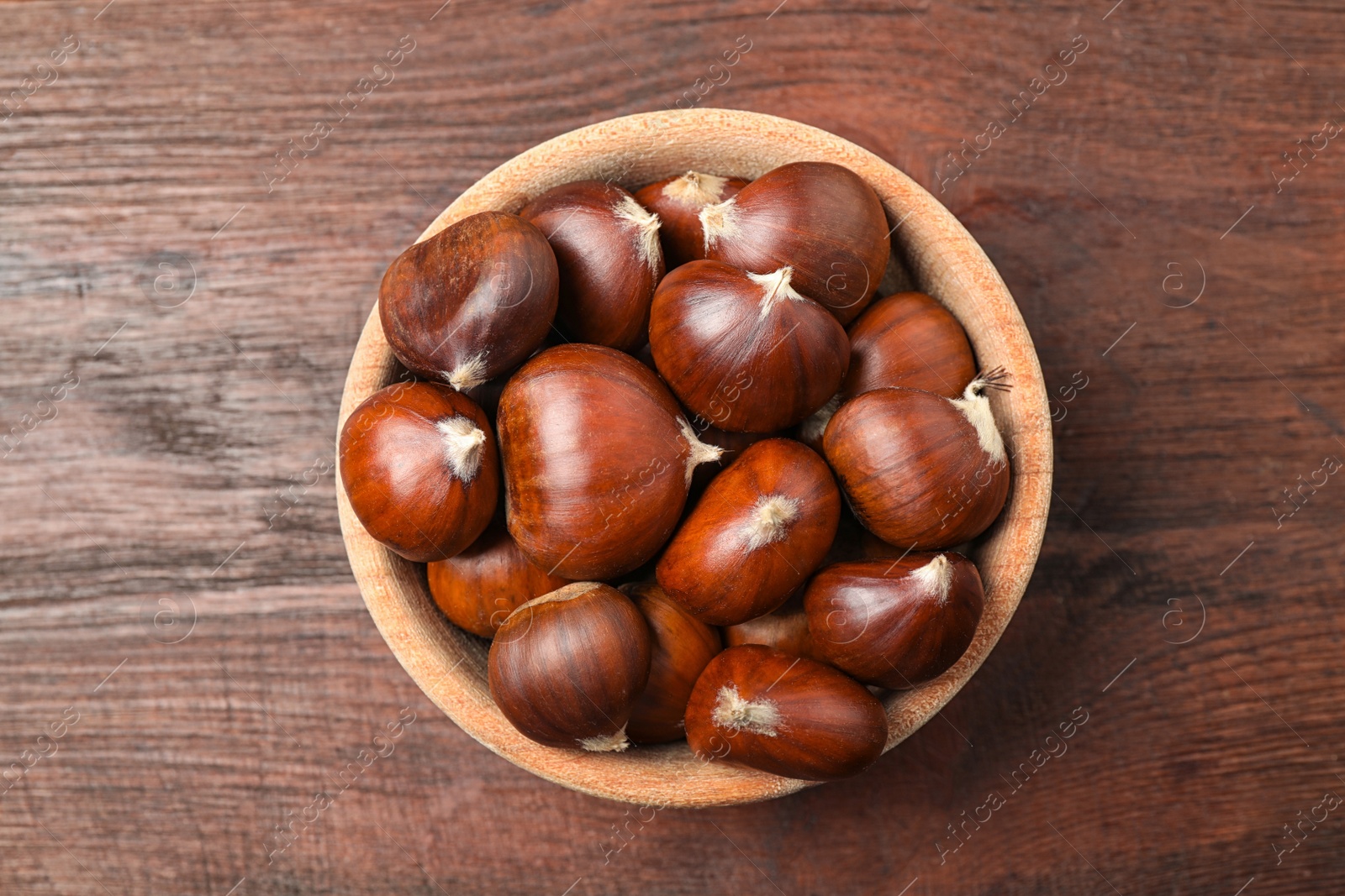 Photo of Fresh sweet edible chestnuts on brown wooden table, top view