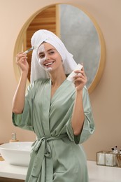 Photo of Woman applying face mask in bathroom. Spa treatments
