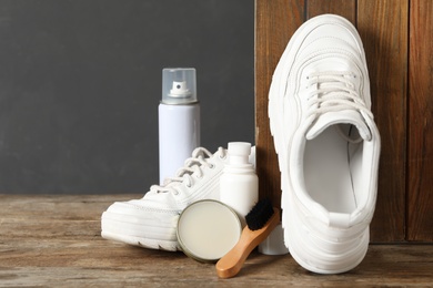 Composition with stylish footwear and shoe care accessories on wooden background