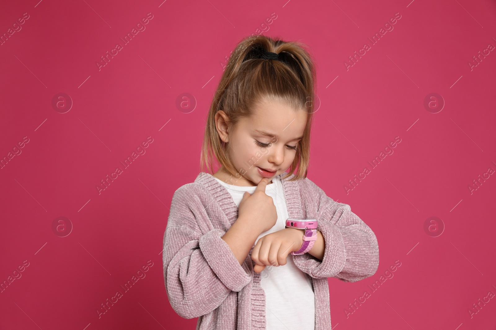 Photo of Little girl with smart watch on pink background