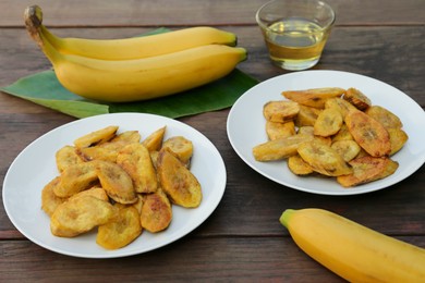 Photo of Tasty deep fried banana slices and fresh fruits on wooden table