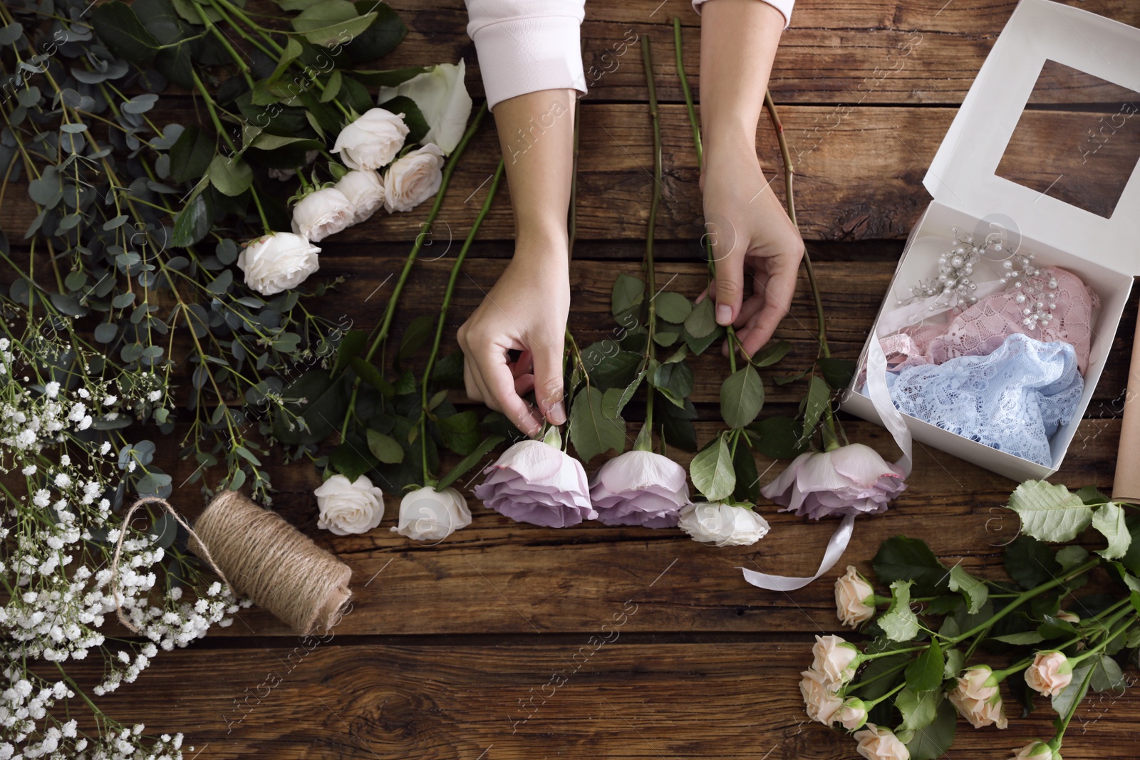 Photo of Florist making beautiful wedding bouquet at wooden table, top view