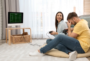 Photo of Happy young couple playing video games at home. Space for text