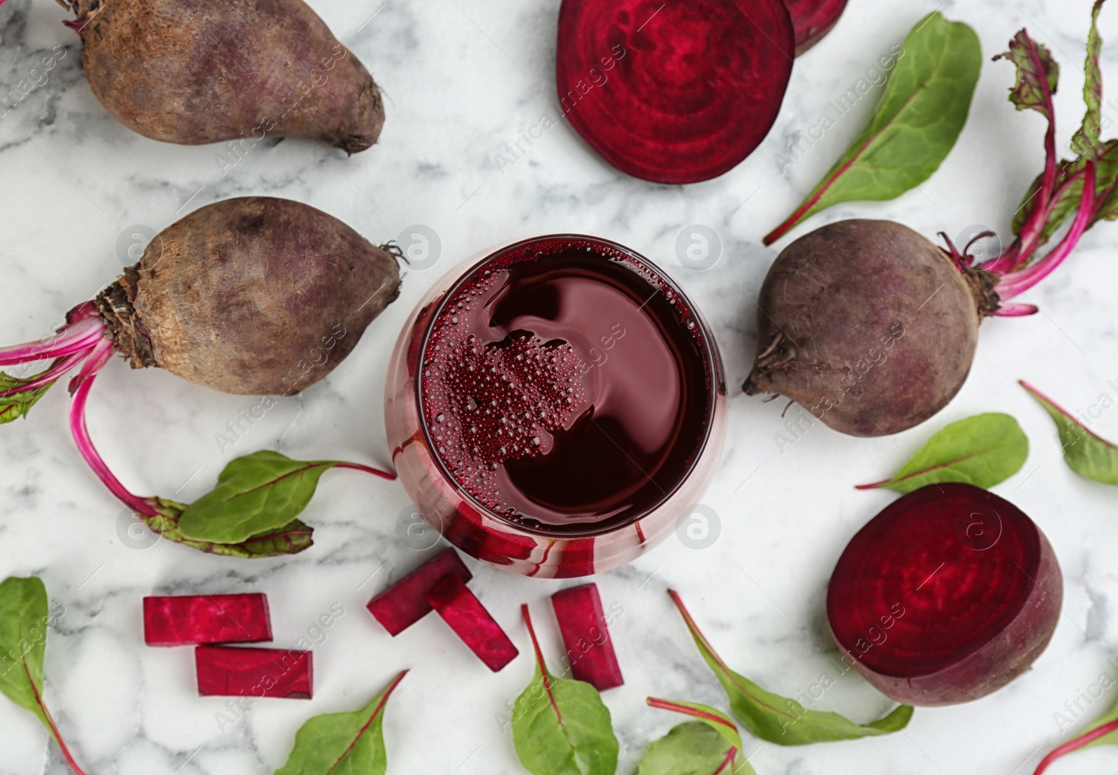 Photo of Freshly made beet juice on white marble table, flat lay