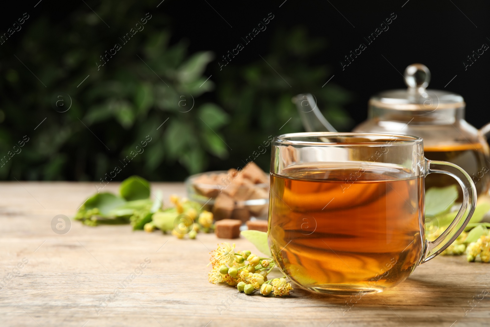 Photo of Cup of tea and linden blossom on wooden table. Space for text