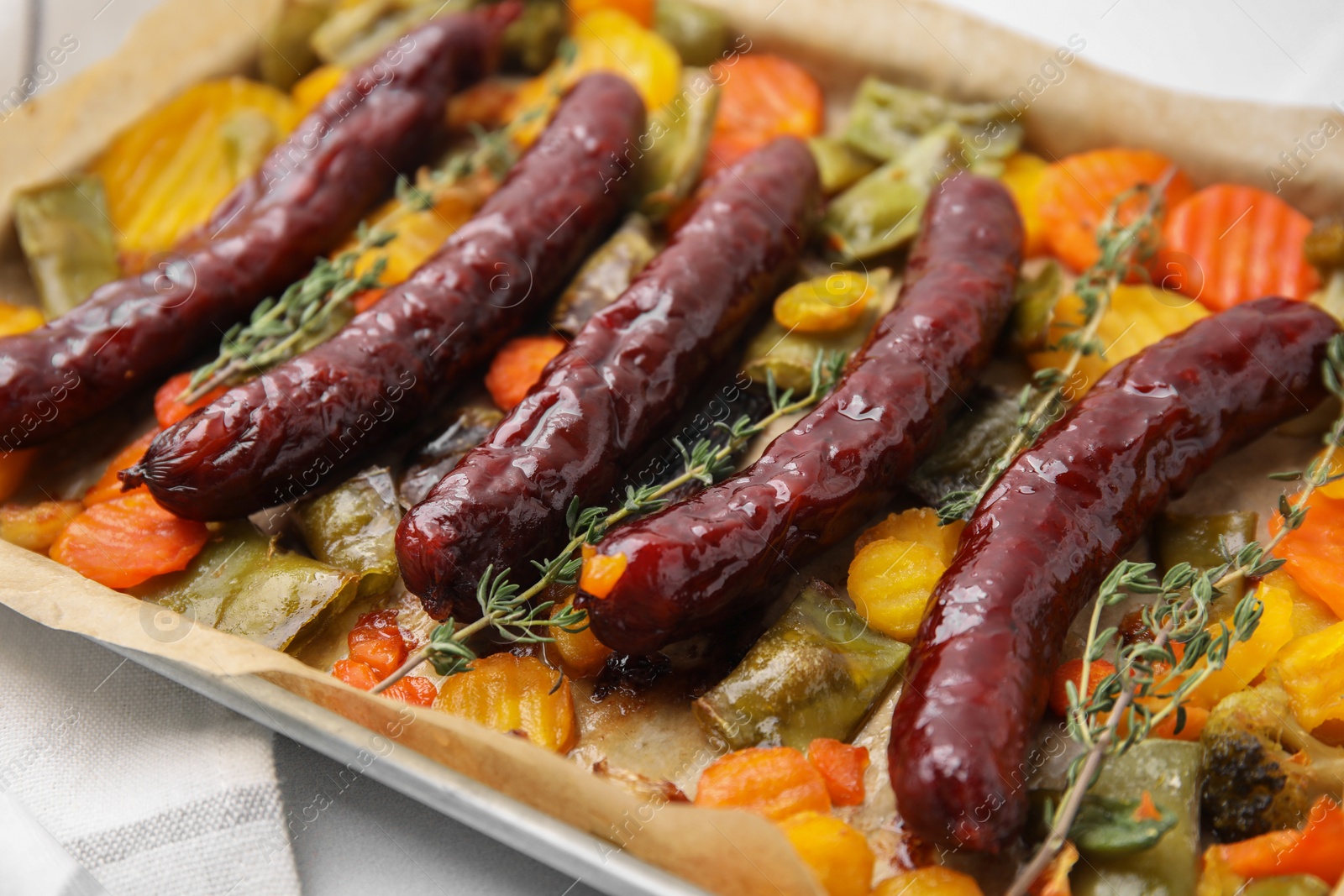 Photo of Baking tray with delicious smoked sausages and vegetables on table, closeup