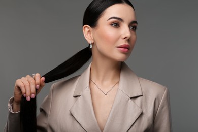 Photo of Beautiful young woman with elegant jewelry on dark grey background