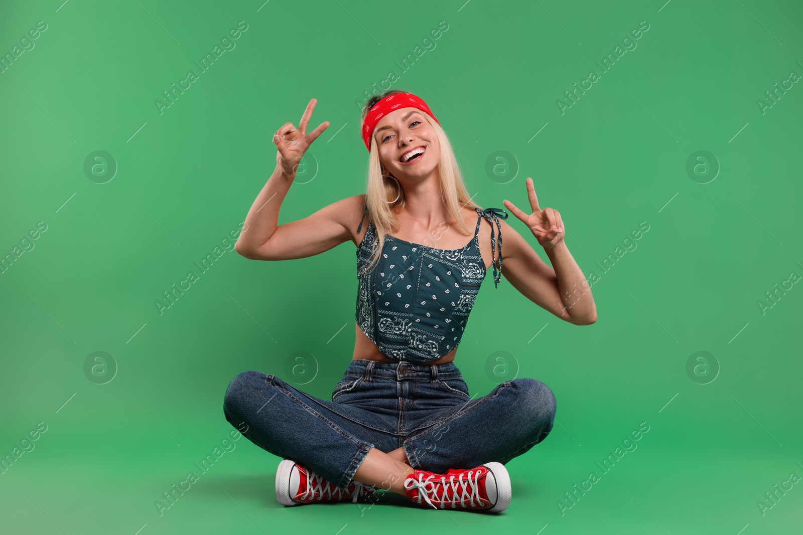 Photo of Portrait of happy hippie woman showing peace signs on green background