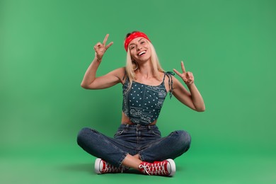 Photo of Portraithappy hippie woman showing peace signs on green background