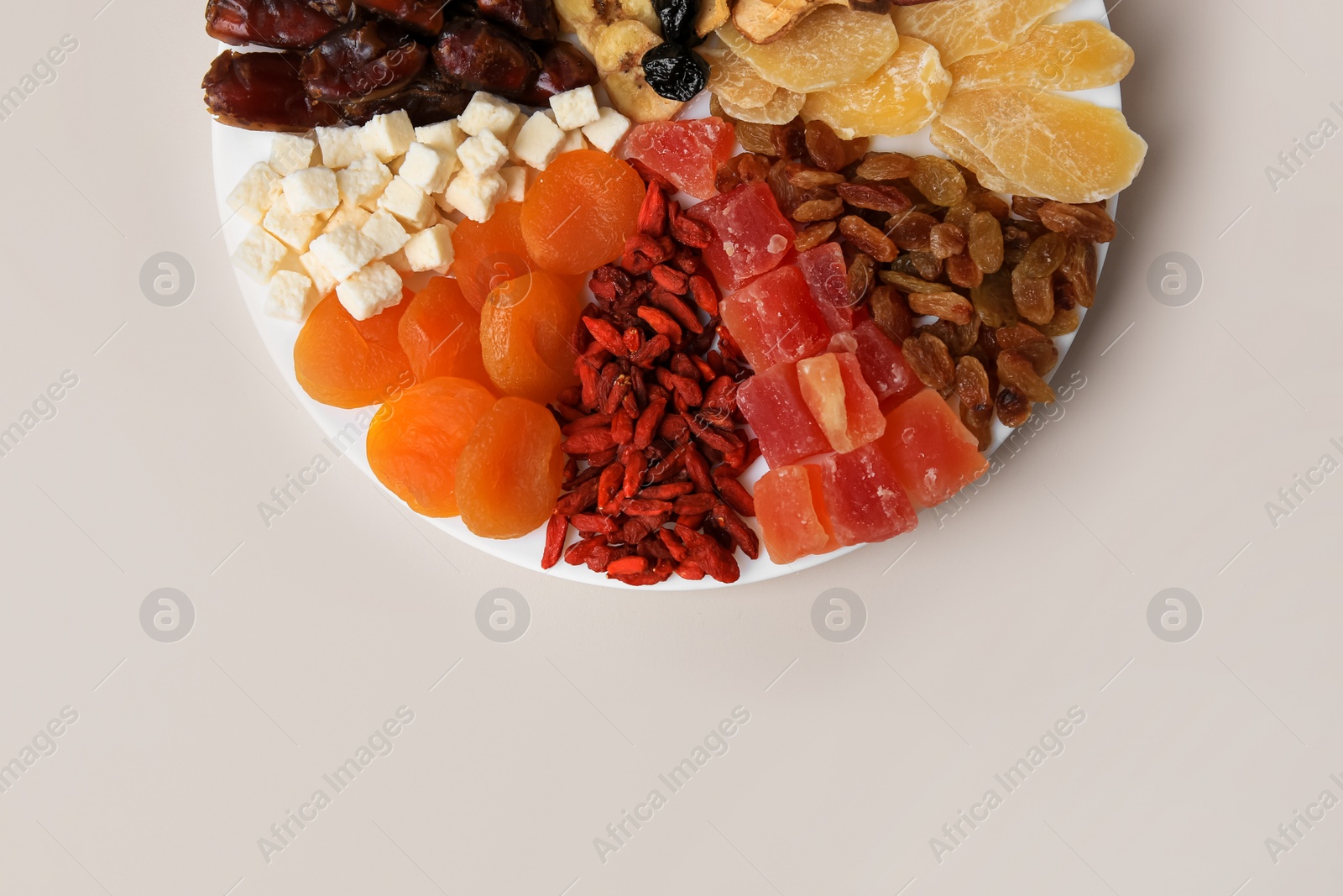 Photo of Plate with different dried fruits on white background, top view. Space for text