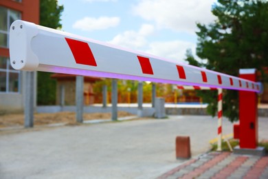 Photo of Closeup view of closed automatic boom barrier outdoors, space for text