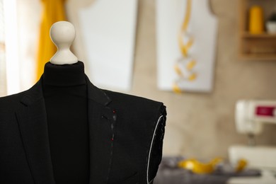 Photo of Mannequin with unfinished suit jacket in tailor shop, closeup. Space for text