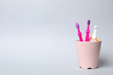 Photo of Baby toothbrushes in holder and space for text on color background