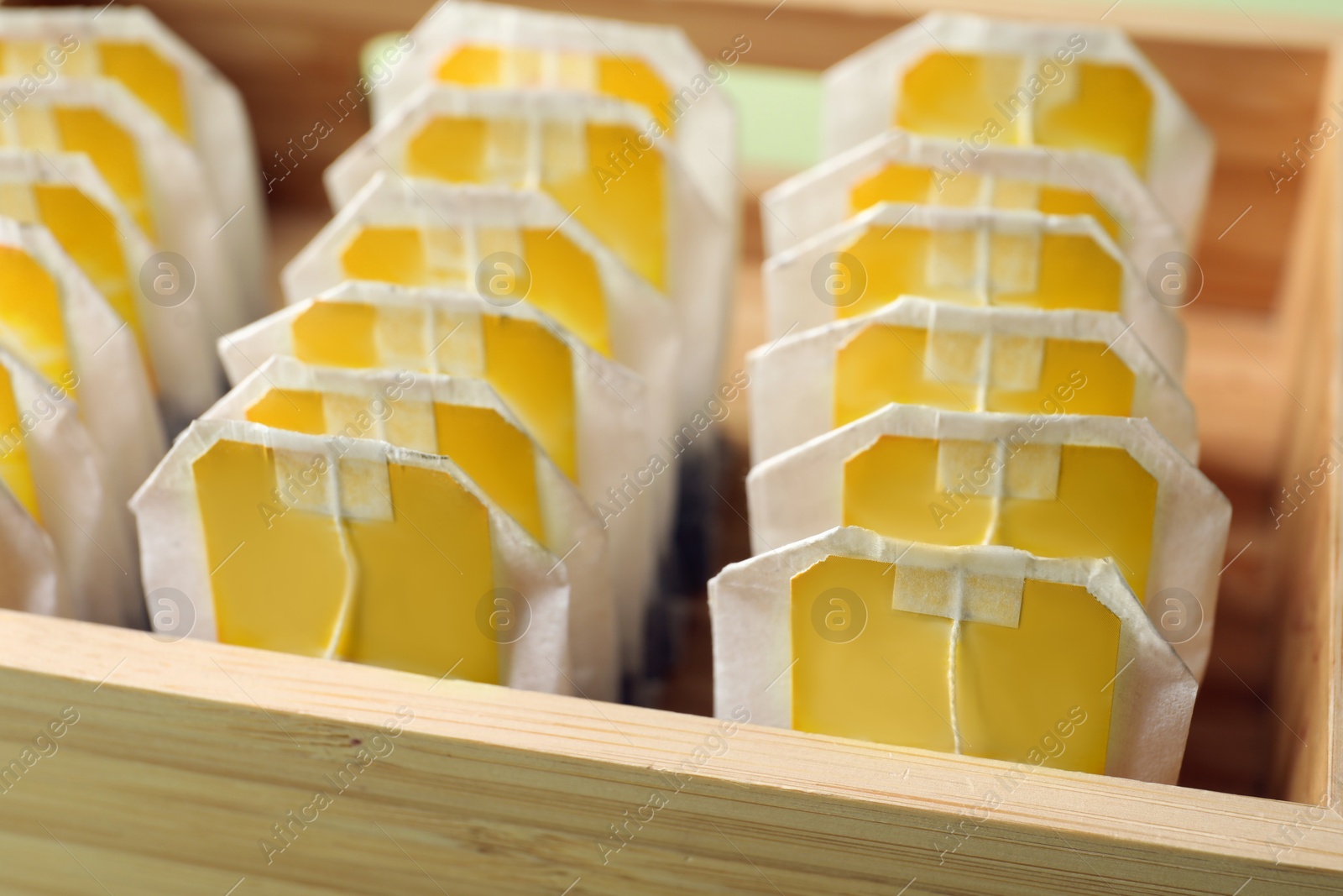 Photo of Paper tea bags with tags in wooden box, closeup