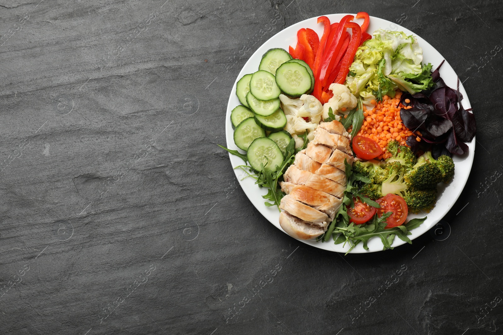 Photo of Balanced diet and healthy foods. Plate with different delicious products on black table, top view. Space for text