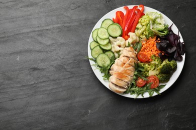 Photo of Balanced diet and healthy foods. Plate with different delicious products on black table, top view. Space for text