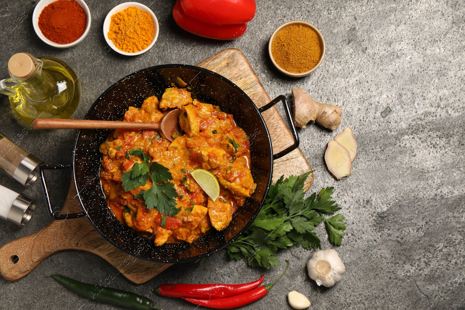 Photo of Delicious chicken curry and ingredients on grey table, flat lay. Space for text