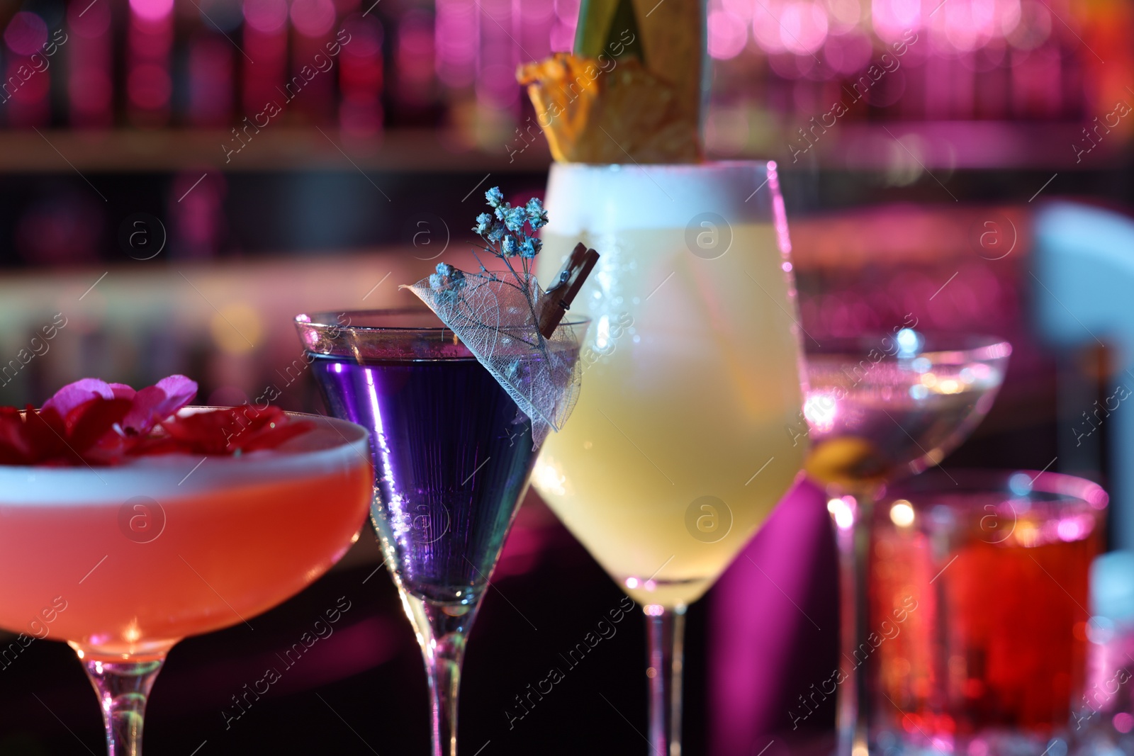 Photo of Different fresh alcoholic cocktails on blurred background, closeup