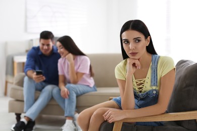 Unhappy woman feeling jealous while couple spending time together at home