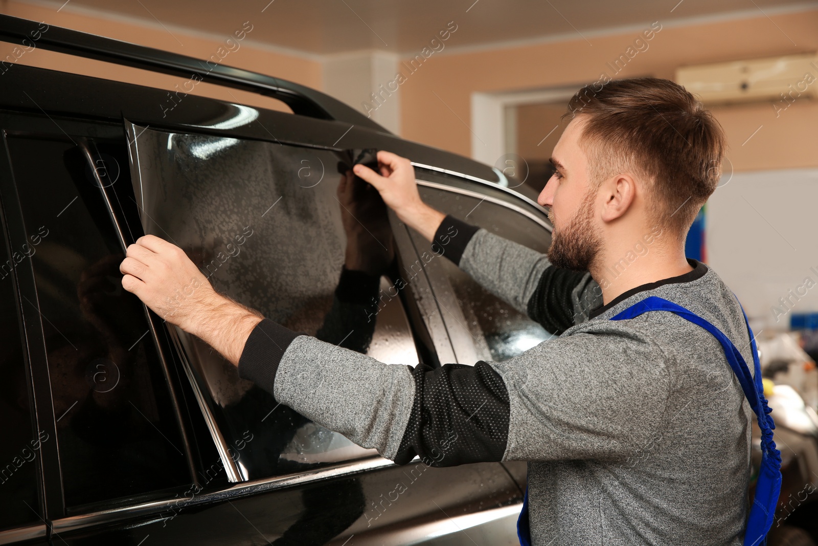 Photo of Worker tinting car window with foil in shop