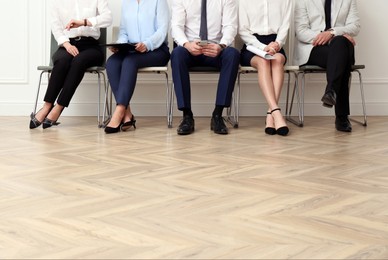 Photo of People waiting for job interview in office hall, closeup