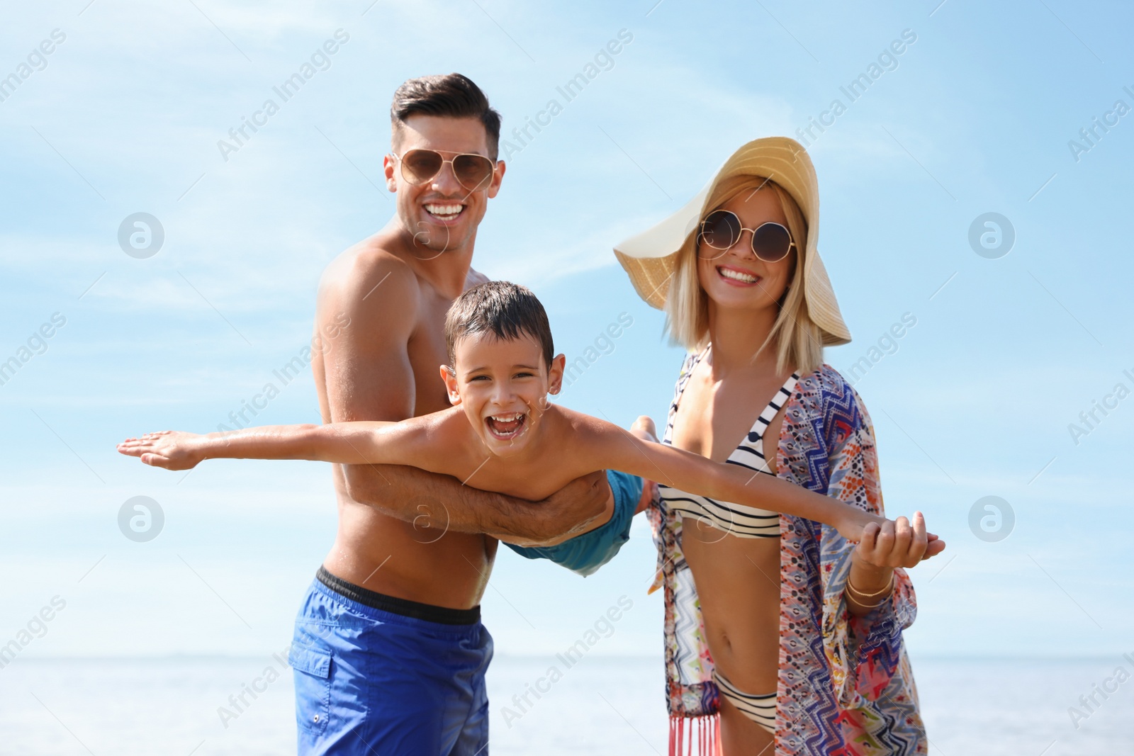 Photo of Parents playing with son at beach. Family vacation