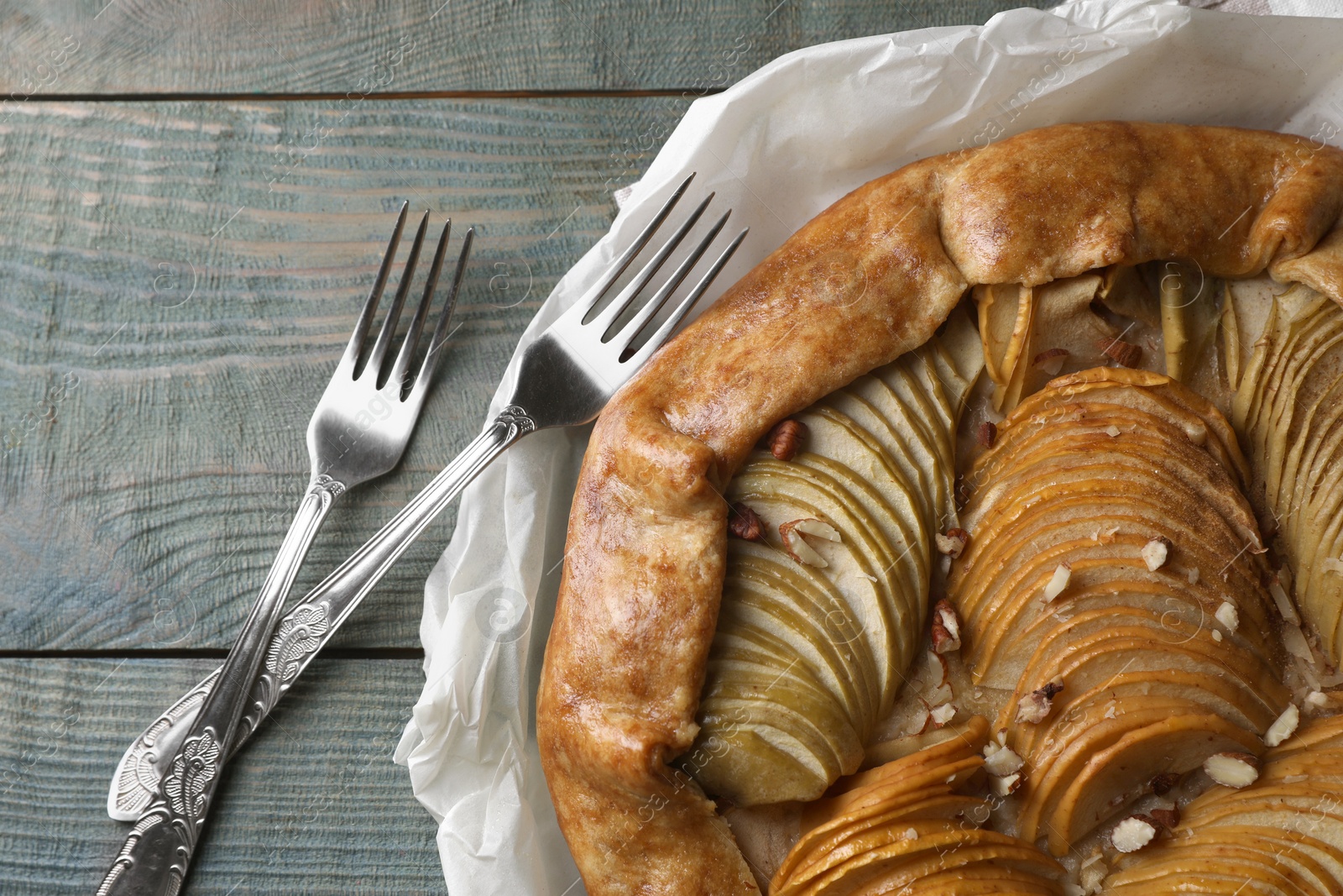 Photo of Delicious apple galette with pecans and forks on wooden table, flat lay